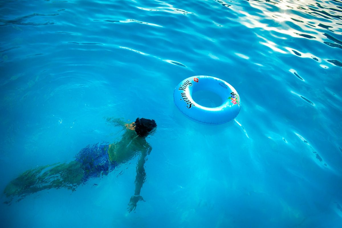 person swimming under body of water near blue inflatable ring