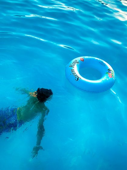 person swimming under body of water near blue inflatable ring