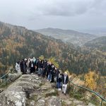 Eine Gruppe von Schülern an einem Aussichtsfelsen mit Berglandschaft