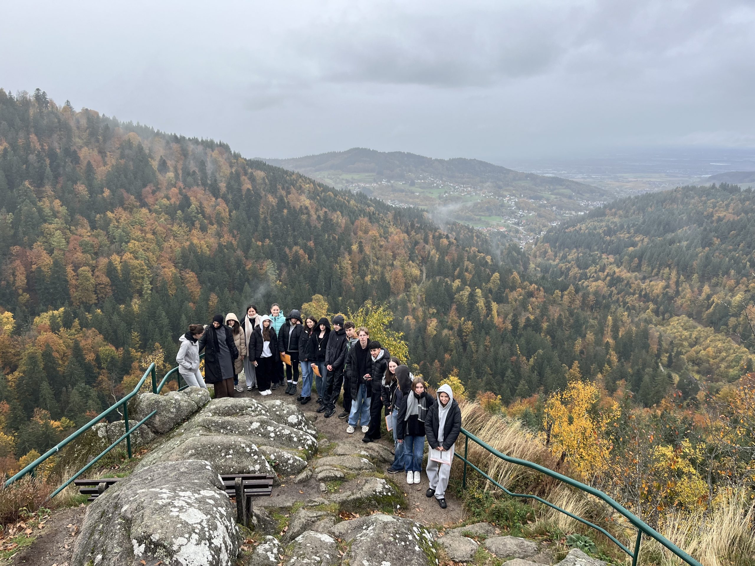 Eine Gruppe von Schülern an einem Aussichtsfelsen mit Berglandschaft