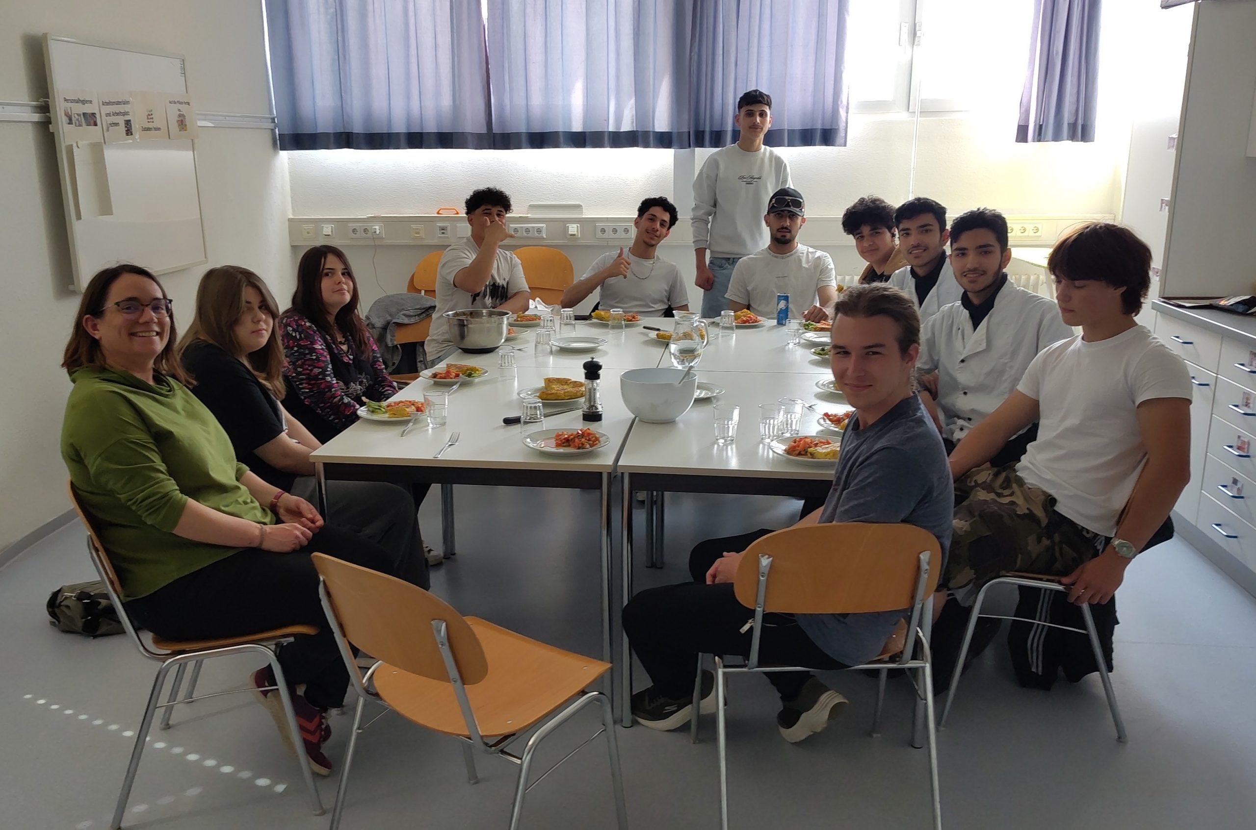 Schüler der VABO sitzen an einem gedeckten Tisch in der Küche.