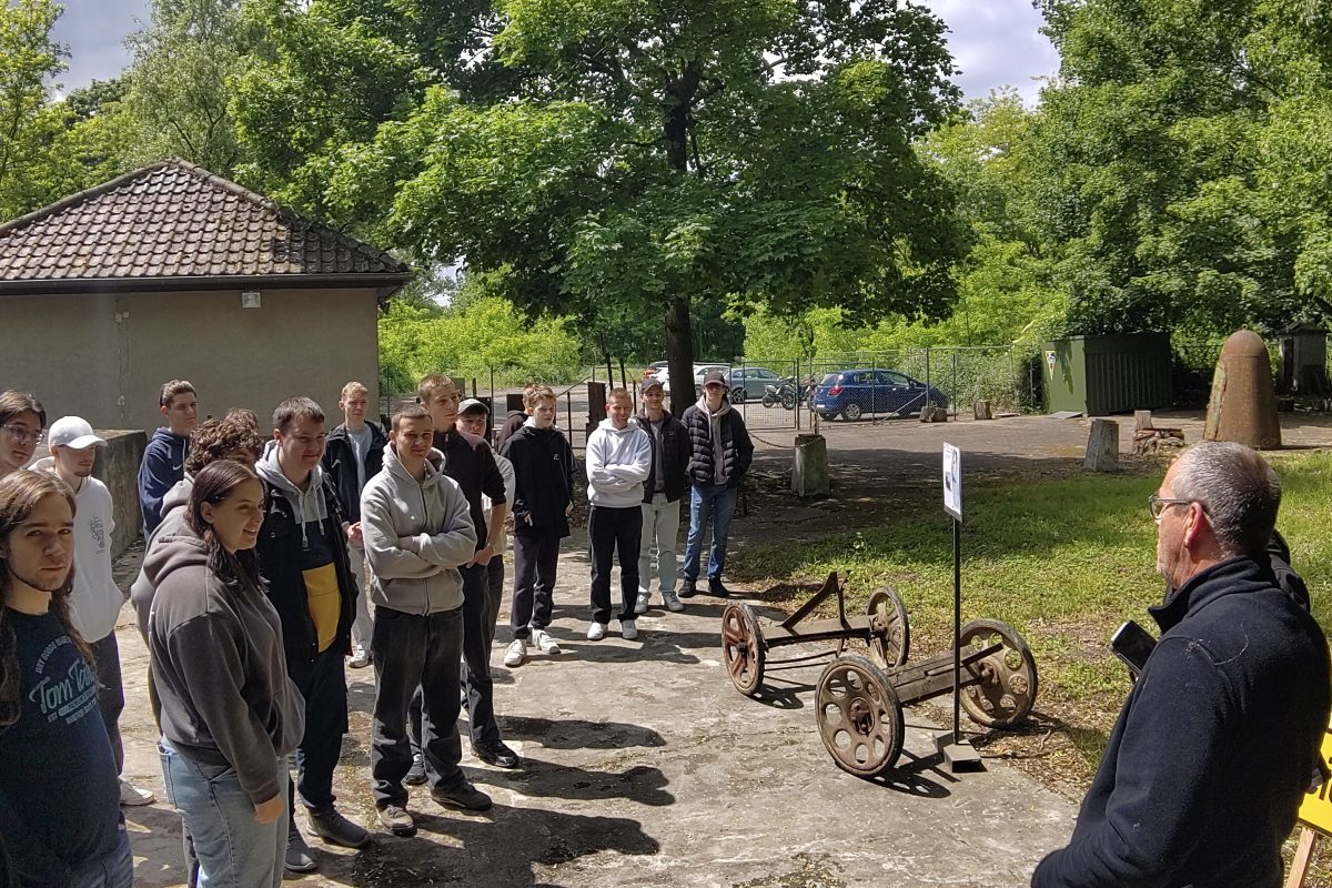 Schülergruppe im Außenbereich vor einem Bunker