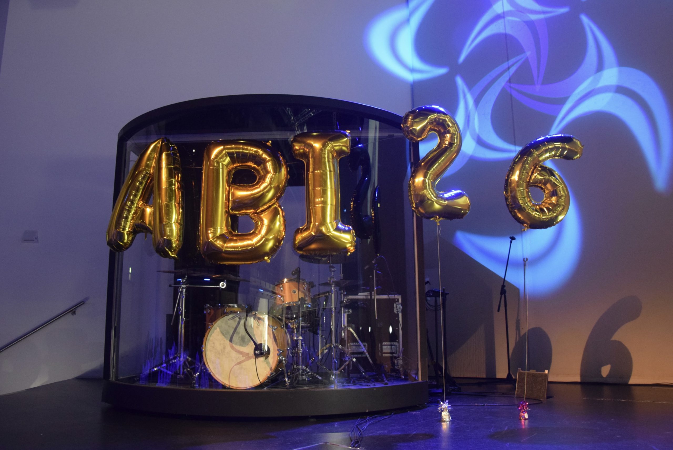 Blau beleuchtete Bühne mit goldenen Buchstaben-Luftballons mit der Aufschrift Abi 2026