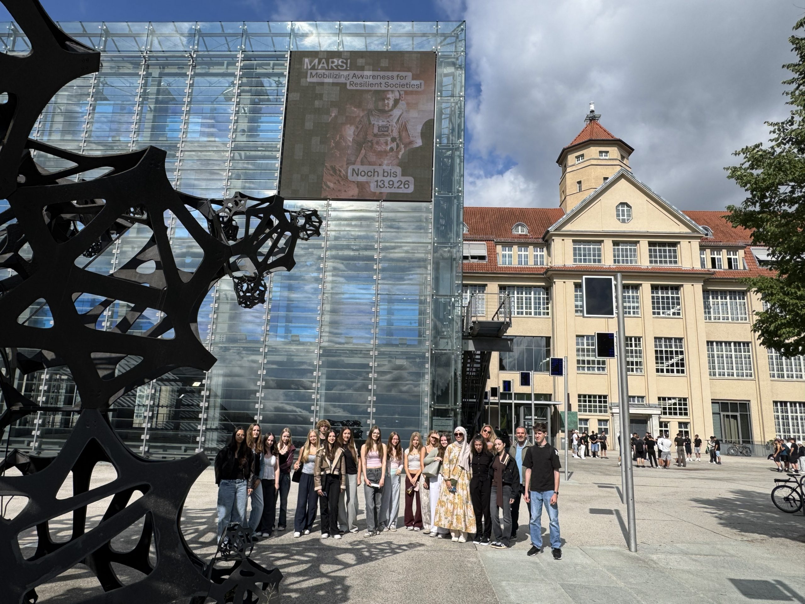 Schulklasse im Vordergrund des ZKM-Gebäudes mit dem blauen Kubus links und dem Eingang rechts