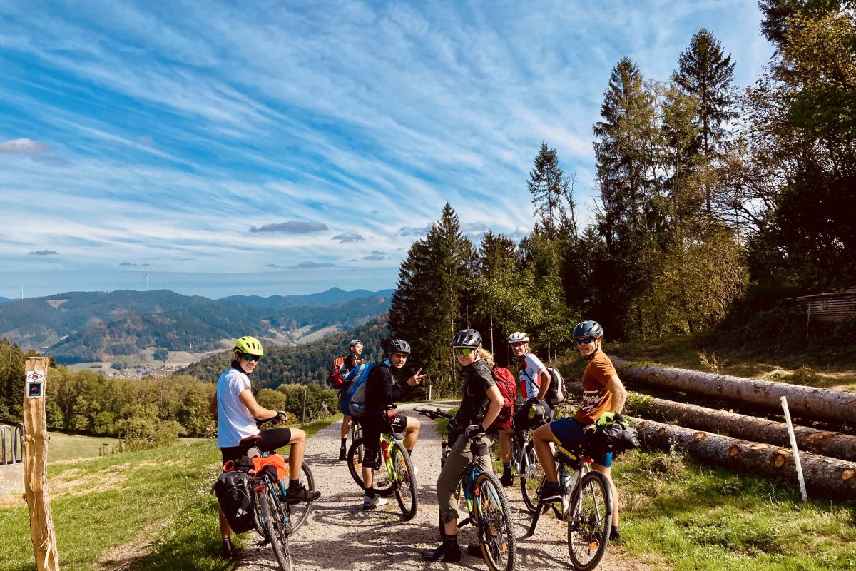Eine Gruppe von Mountainbikern steht auf einem Weg in der Landschaft.